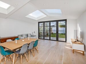 "Contemporary aluminium bifold doors fully open to a bright Walton Surrey living room with garden view"